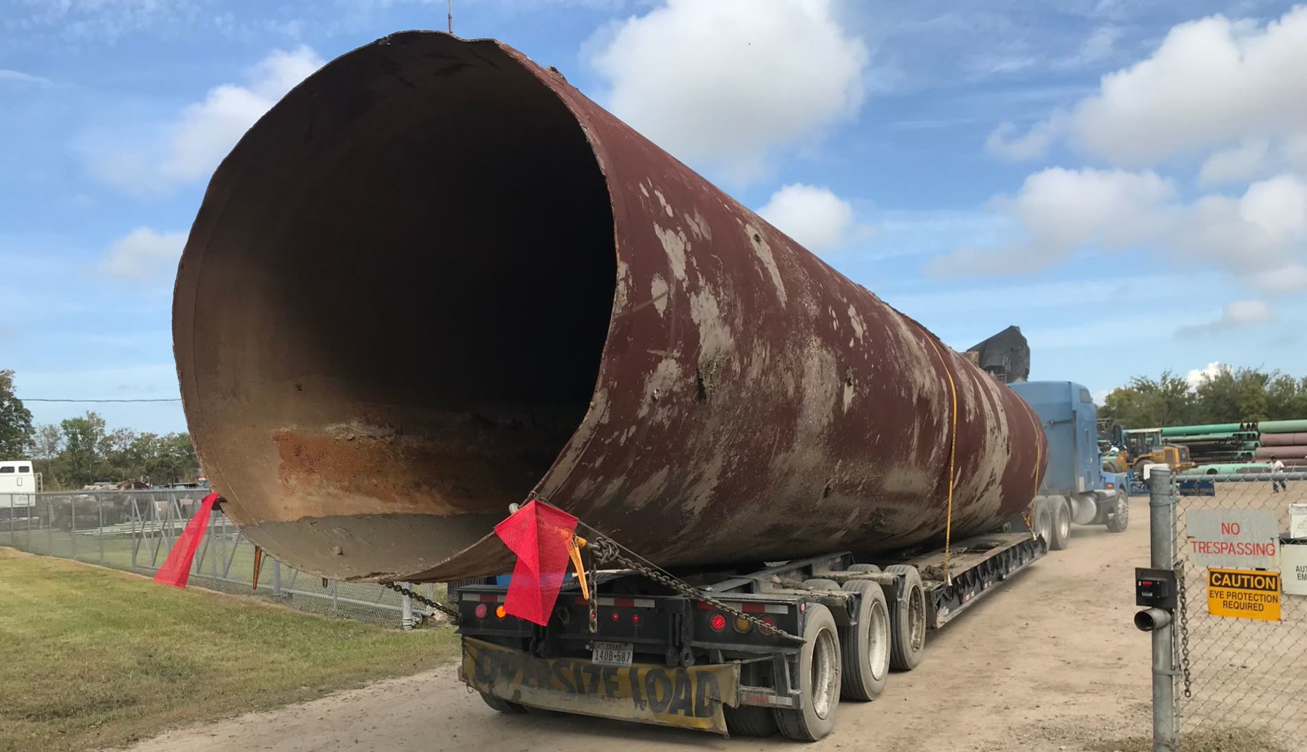 Large-diameter recovered pipe leaving the yard on an oversize load