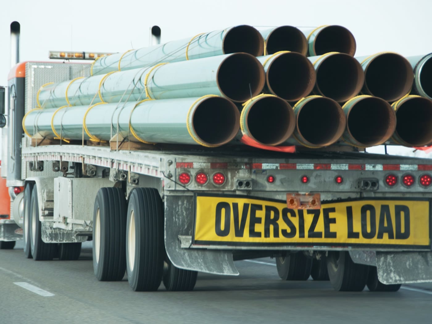 Flatbed load of line pipe under way on the highway