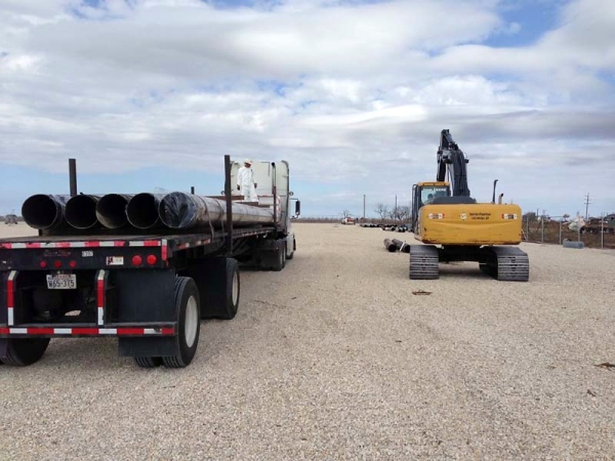 Recovered line pipe loaded on a flatbed with an excavator standing by