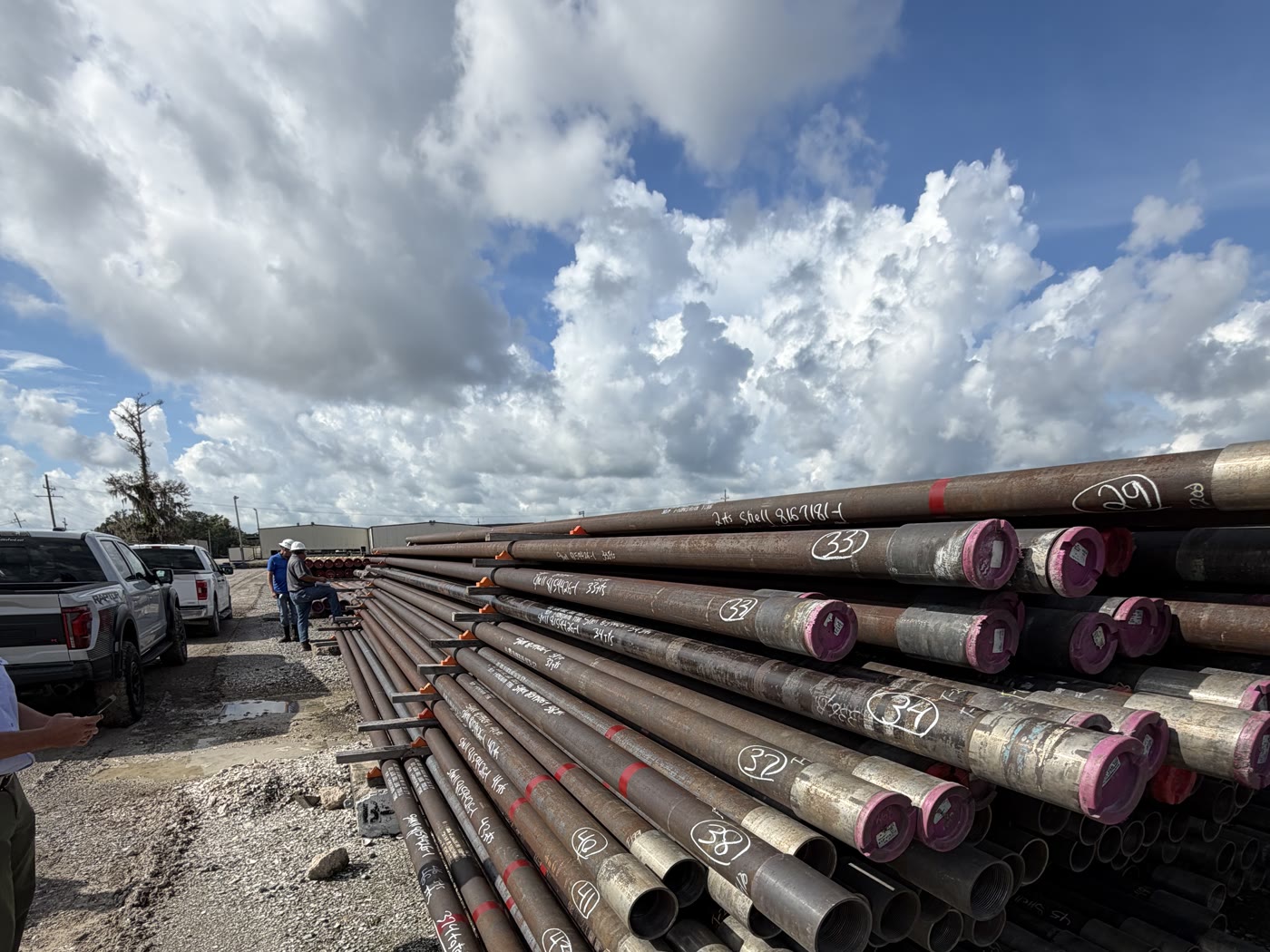 Capped pipe ends with size markings, stacked in the yard